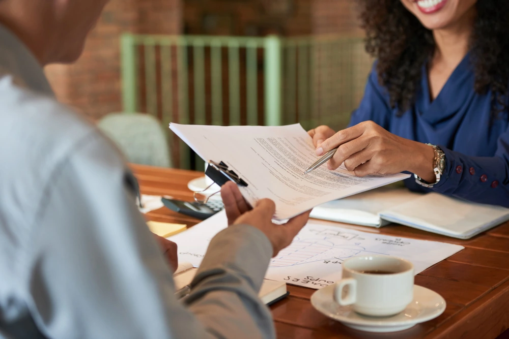 Une professionnelle souriante présente un document à un client assis en face d'elle